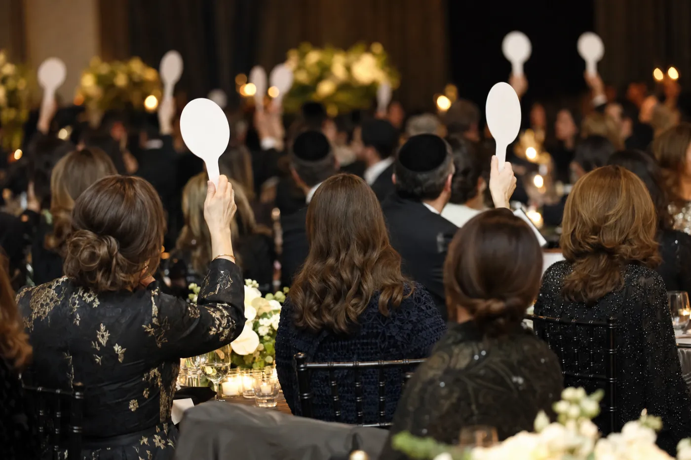 Guests raising bidding paddles at a black-tie charity auction